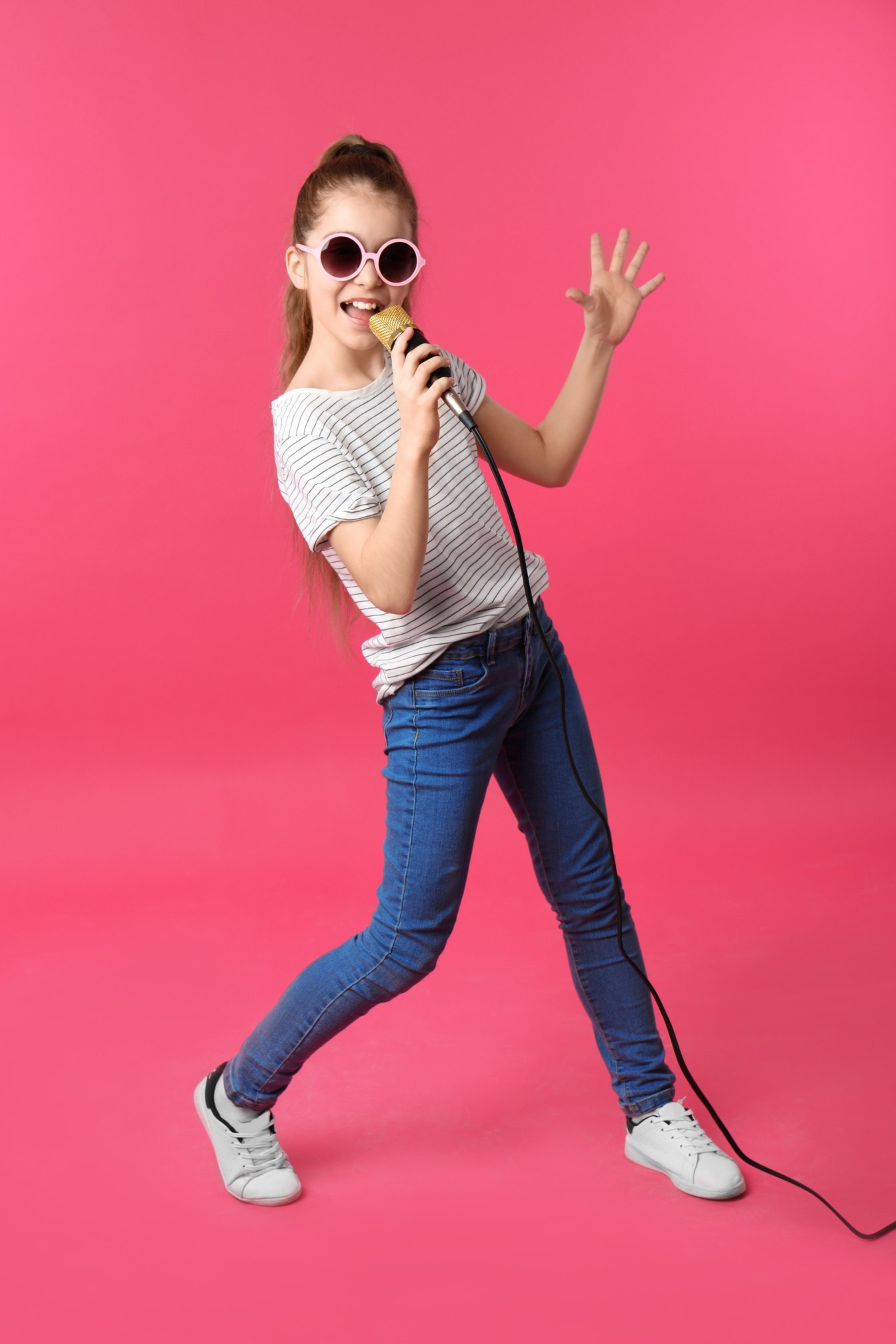 Cute Girl Singing in Microphone on Color Background